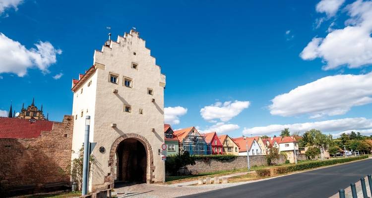 Porte historique avec des maisons aux couleurs vives à proximité.