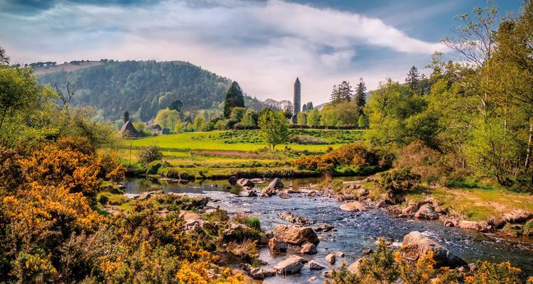 A picturesque river scene with a distant round tower and hills.