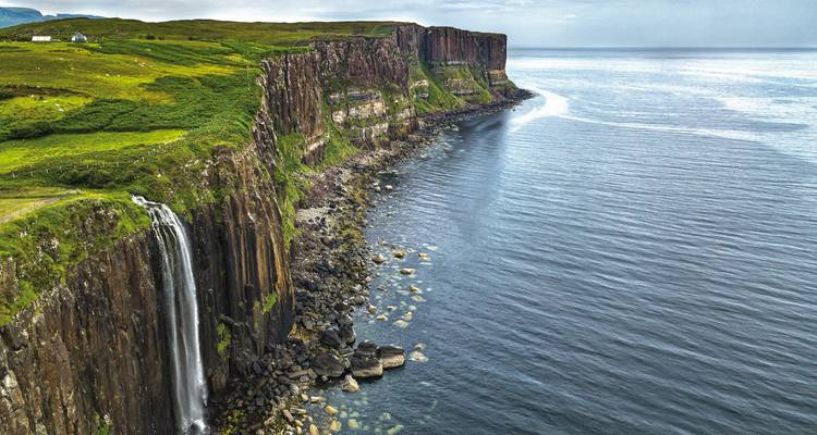 Meeresklippen mit einem Wasserfall, der ins Meer fließt.