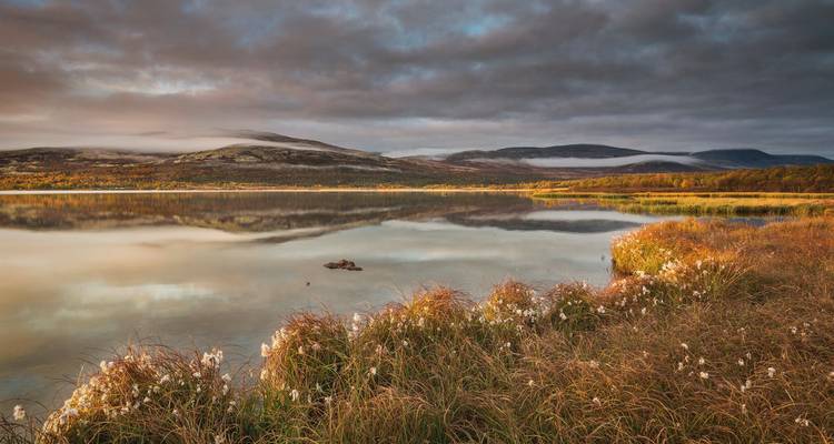Friedliche Seeszene mit Bergen und Wolken.