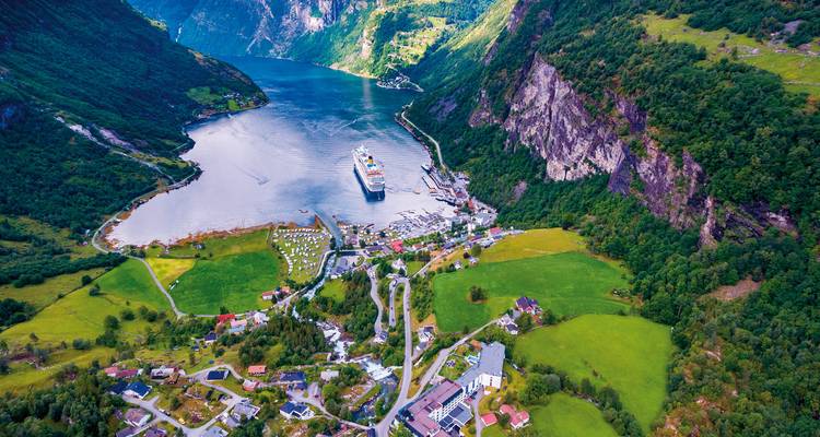 Aerial view of a fjord village with surrounding mountains.