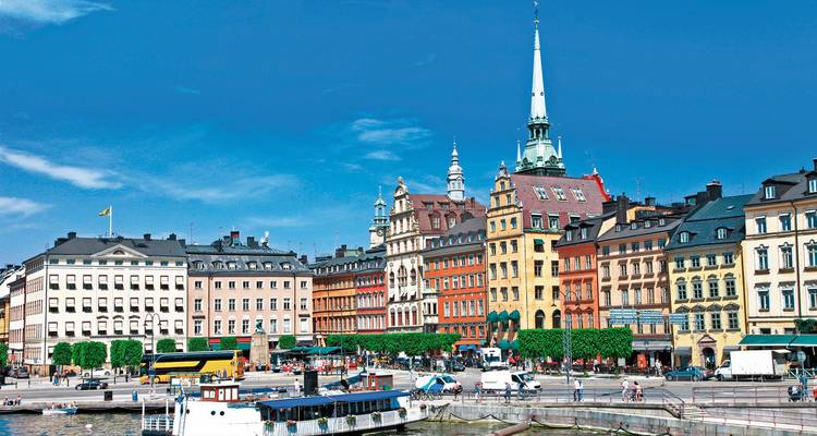 Colorful historic buildings and spires by a waterfront.