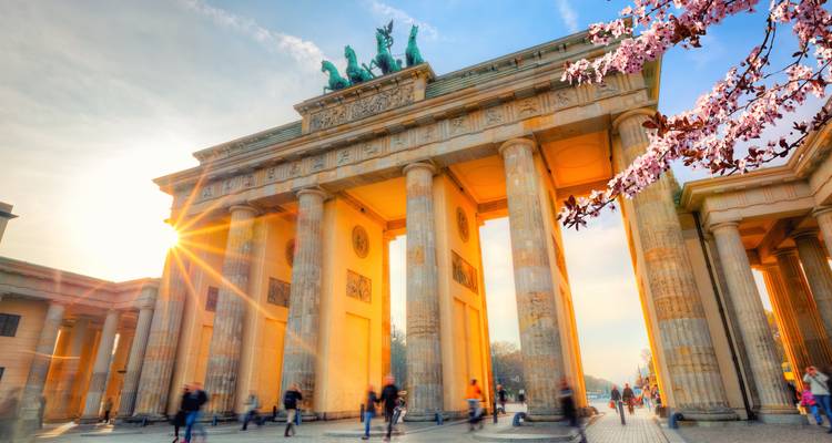 Brandenburg Gate with cherry blossoms and a sun flare.