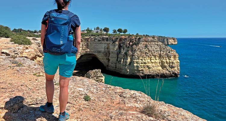 Wanderer steht am Klippenrand mit Blick auf das Meer.