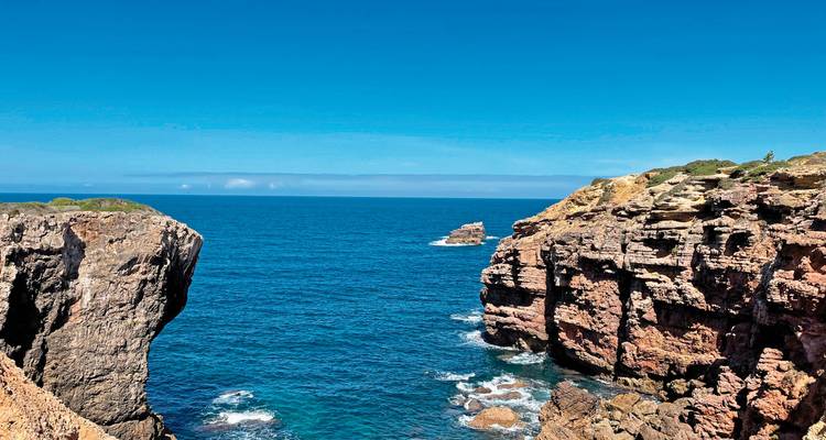 Falaises côtières avec océan bleu et ciel dégagé.