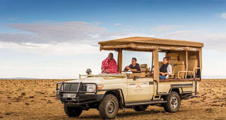 Gruppe von Menschen in einem Safari-Fahrzeug in der Savanne.
