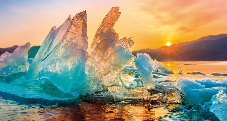 Close-up of jagged ice formations with a warm sunset in the background.