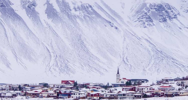 Snow-covered small town nestled against a backdrop of large snow-covered mountains.