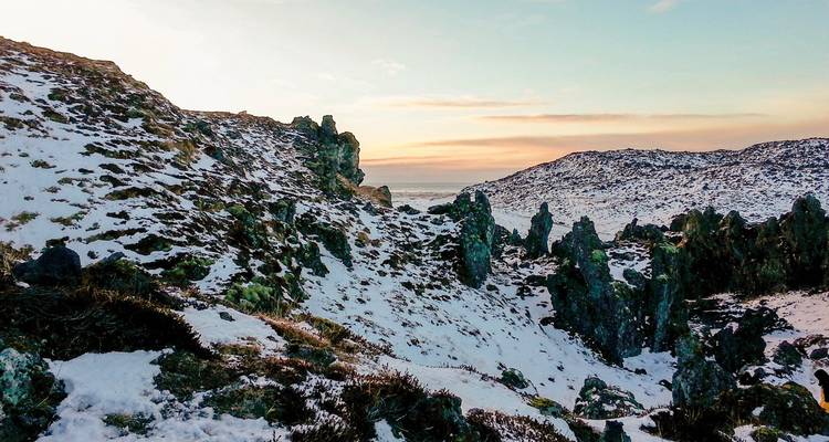 Besneeuwde rotsige landschap met een schemerluchten.