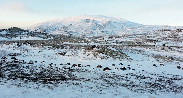 Besneeuwde vulkanische landschap met een verre berg.