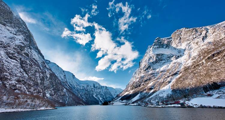 Frozen fjord surrounded by steep cliffs and snow.
