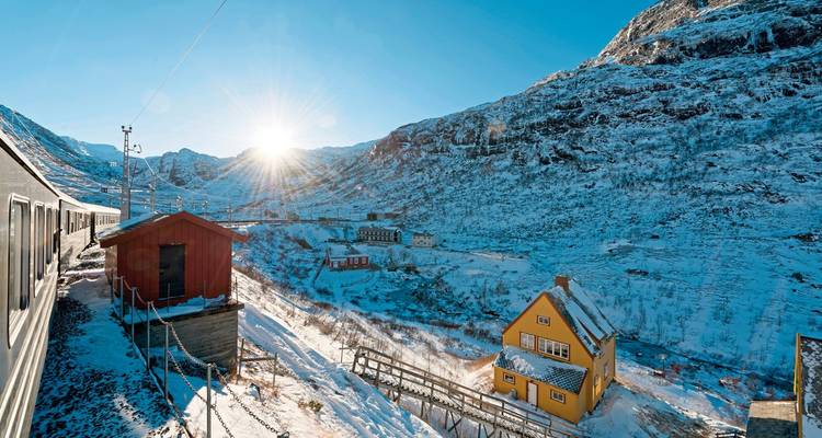 Train passing through a snowy landscape with wooden houses.