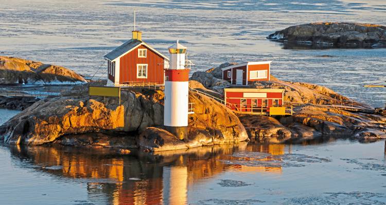 Petite île avec phare et maisons rouges dans l'eau glacée.