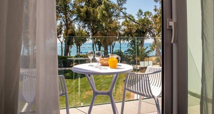 Balkonuitzicht met gedekte tafel en oceaan op de achtergrond.