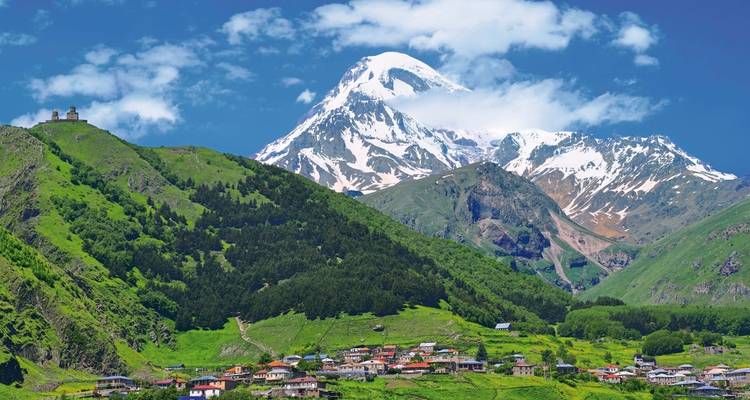 Village at the foot of a snow-capped mountain with a church