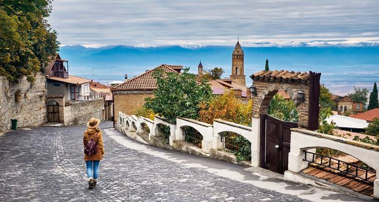 Person walking down a cobblestone street in a historic town