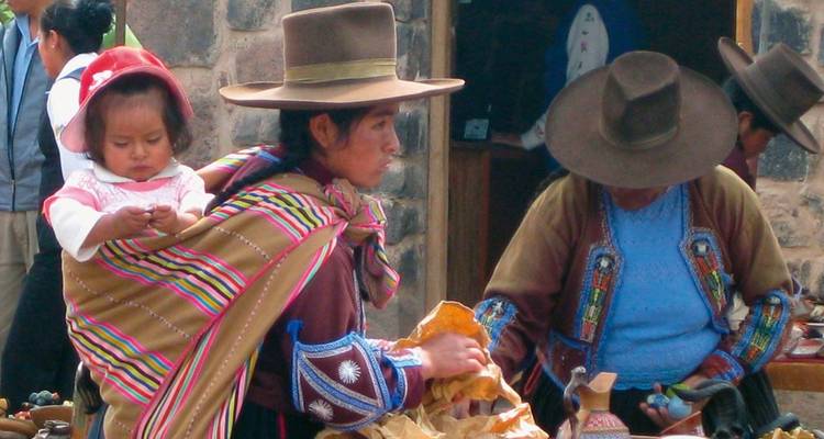 Frauen in traditioneller Kleidung mit einem Kind in einem gewebten Tragetuch.