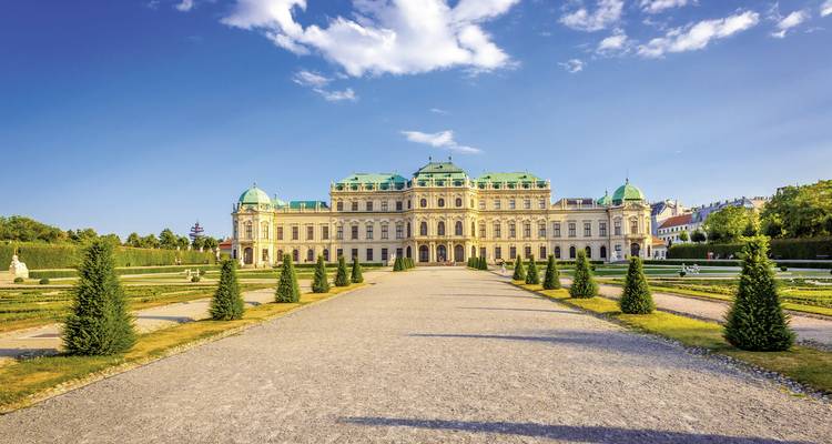 A grand Baroque style palace with manicured gardens and a clear blue sky.