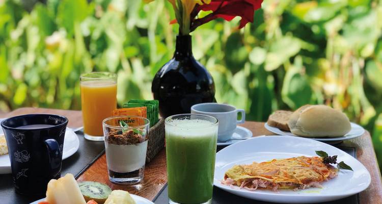 A close-up of a breakfast table set with various dishes, drinks, and condiments.