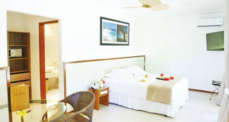 Bright hotel room with a large bed, modern decor, and an adjoining bathroom.