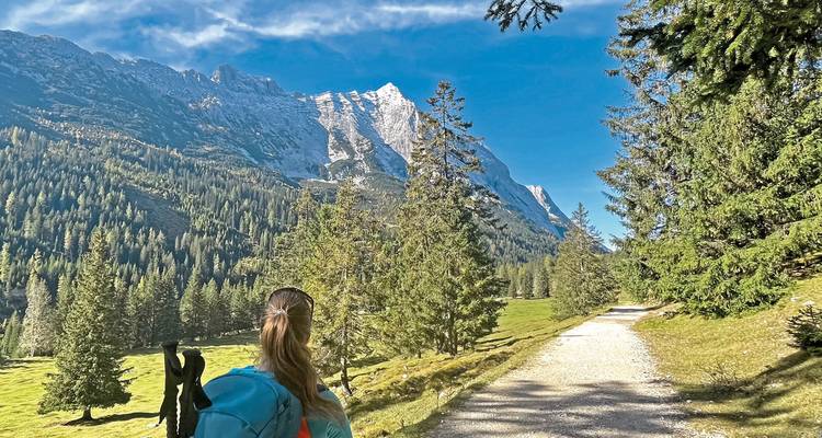 Een wandelaar die loopt op een pad met bergen in de verte.