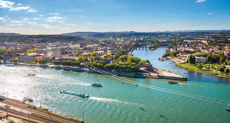 Luftaufnahme einer Stadt mit zusammenfließenden Flüssen und einer belebten Uferpromenade.