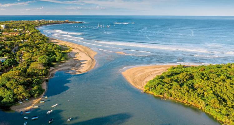 Luftaufnahme einer Flussmündung, die auf das Meer trifft.