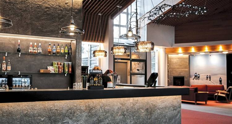 Hall d'hôtel moderne avec un bar et un coin salon.