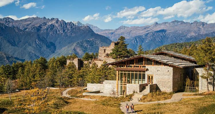 Steingebäude in bergiger Umgebung mit Menschen, die in der Nähe spazieren gehen.