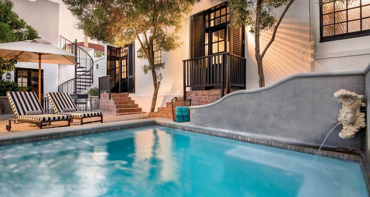 Charming poolside setting with striped loungers and umbrellas.