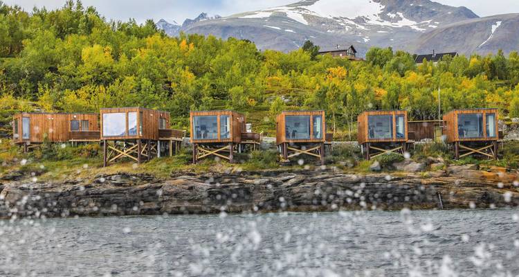 Hütten auf Stelzen an einem See mit Herbstlaub.