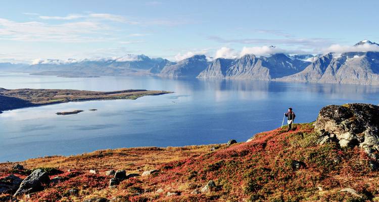 Wanderer auf einem Hügel mit weiter Berg- und Seeaussicht.