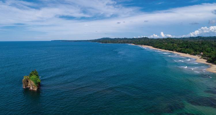 Scenic coastline with clear blue water and a distant green landscape.