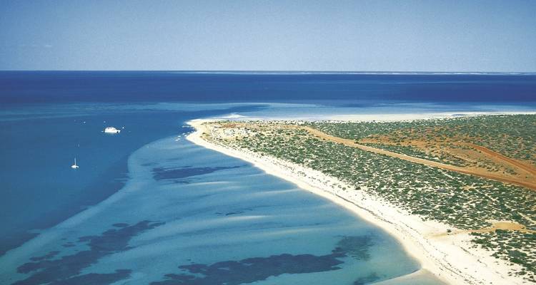 Vue aérienne d'un paysage côtier avec un océan bleu et des rivages sablonneux.