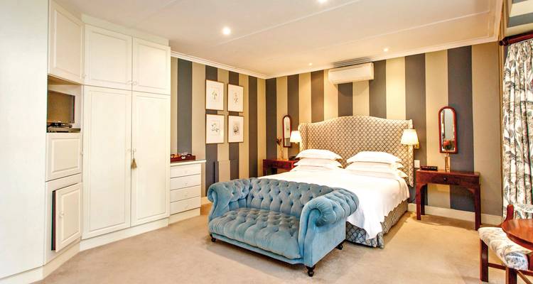 Elegant eingerichtetes Schlafzimmer mit blauem Sofa und gemusterter Tapete.