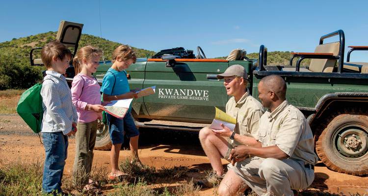 Guides und Kinder in der Nähe eines Safari-Fahrzeugs mit Kwandwe-Branding.