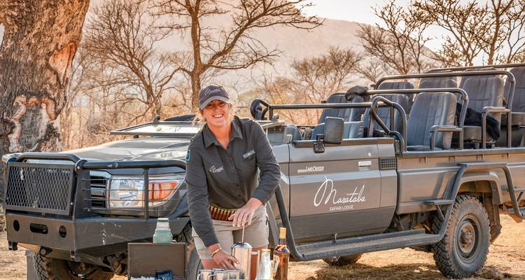 Un guide de safari préparant des rafraîchissements à côté d'un véhicule ouvert.