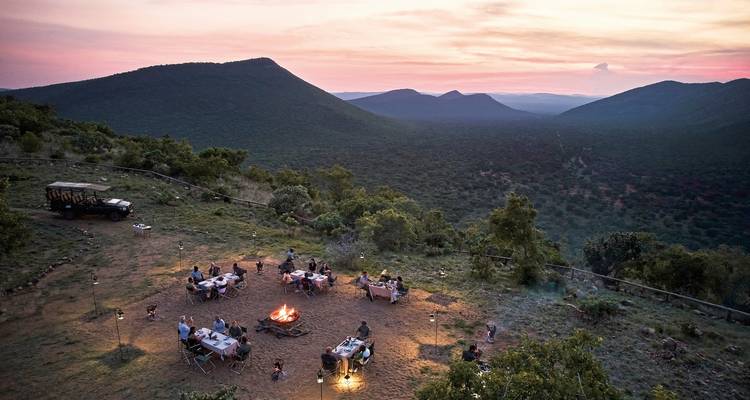 Buiteneetgelegenheid met kampvuur en schilderachtig uitzicht bij zonsondergang.