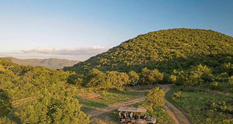 Schilderachtig uitzicht op groene heuvels met een safarivoertuig.