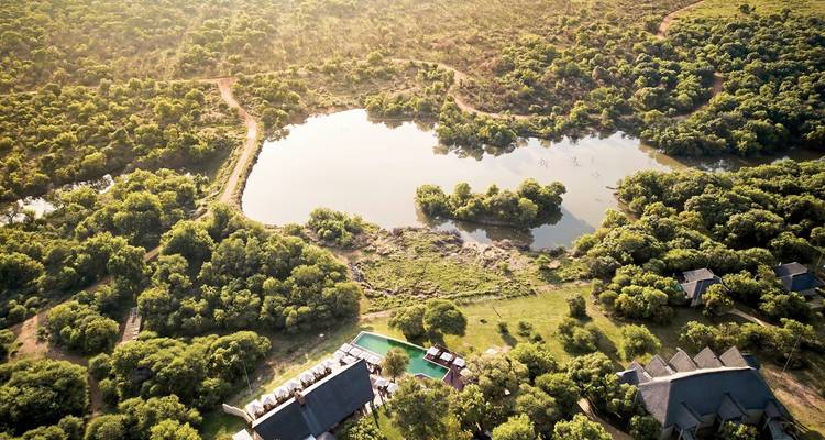 Luchtfoto van weelderig bos en een centraal meer.