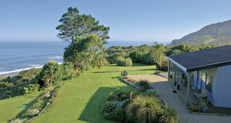 A coastal house with a large garden overlooking the ocean.