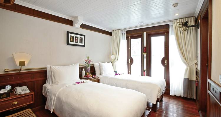 Chambre d'hôtel confortable avec deux lits et un balcon.