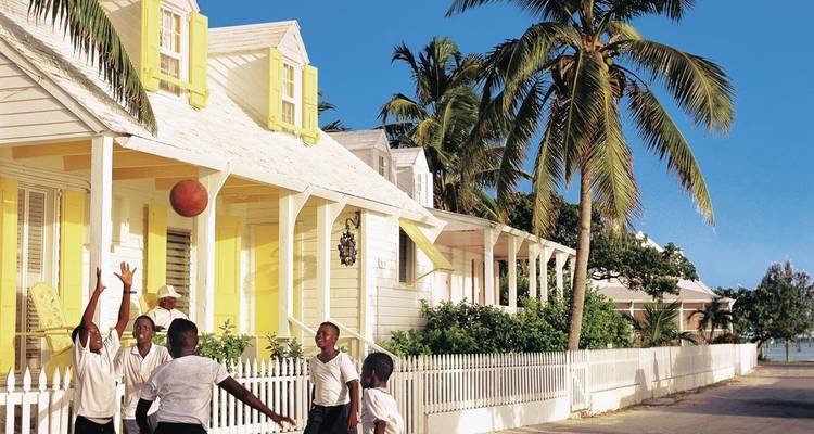 Children playing with a ball in front of colorful houses.