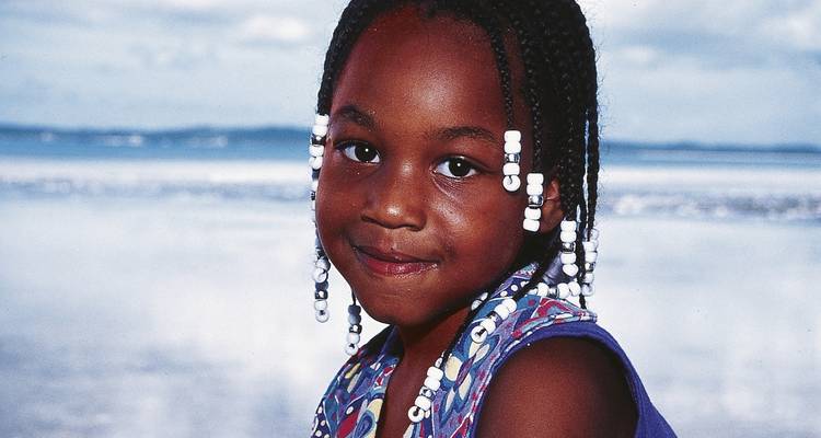Portrait en gros plan d'une jeune fille avec des tresses sur une plage.