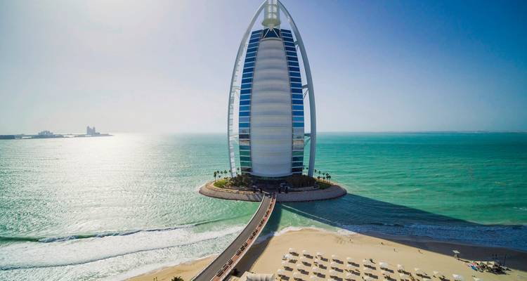 Burj Al Arab mit klarem Meer und Strand im Vordergrund.