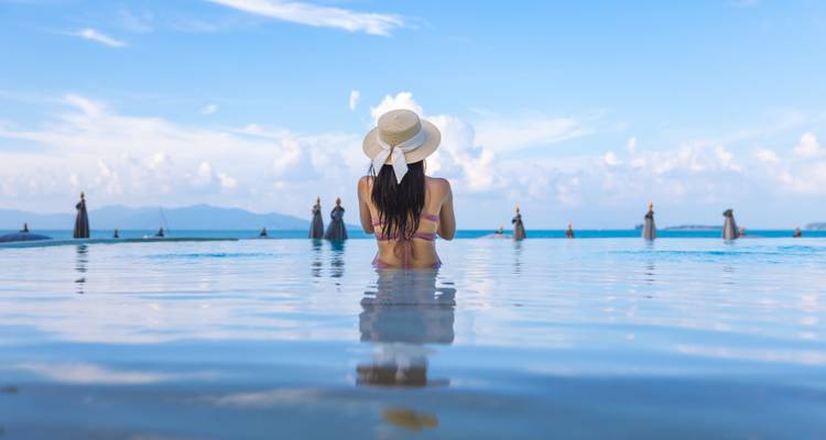 Person in einem Pool mit Infinity-Blick über das Meer und die Inseln.