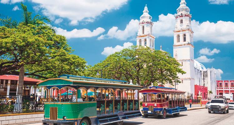 Street with colorful tour buses and a white twin-tower church