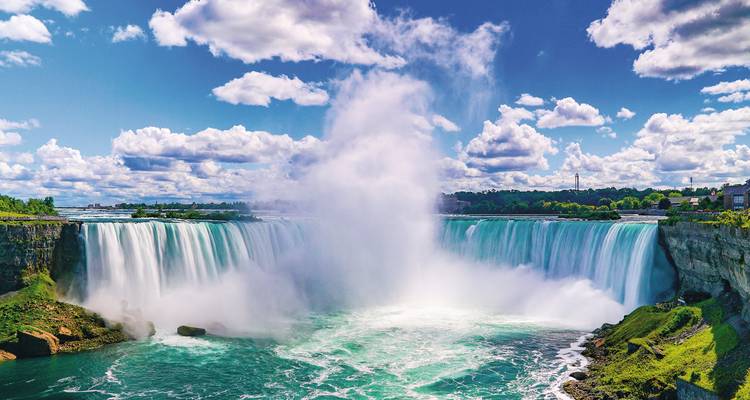 Cascade époustouflante avec brume et nuages en arrière-plan.
