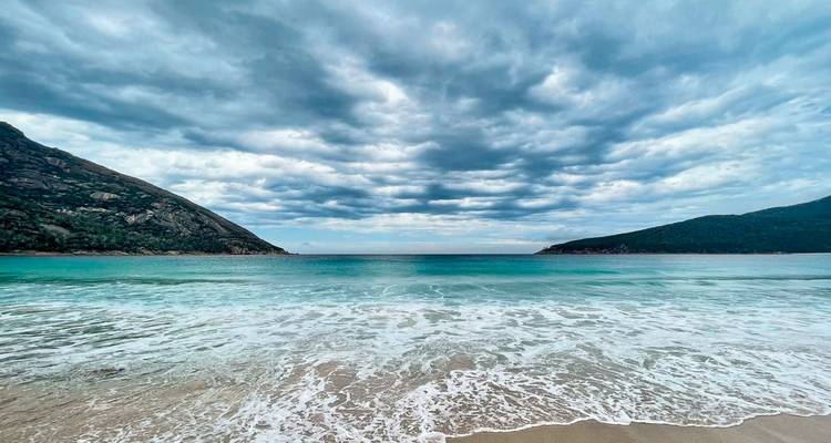 Scenic beach with blue water and cloudy sky.
