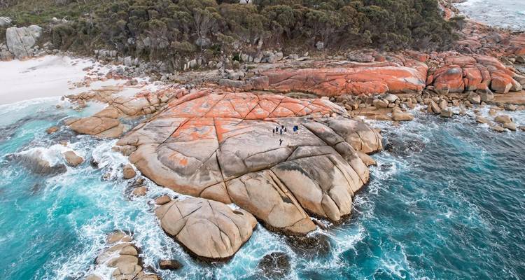 Aerial view of a rocky shoreline with bright ocean water.